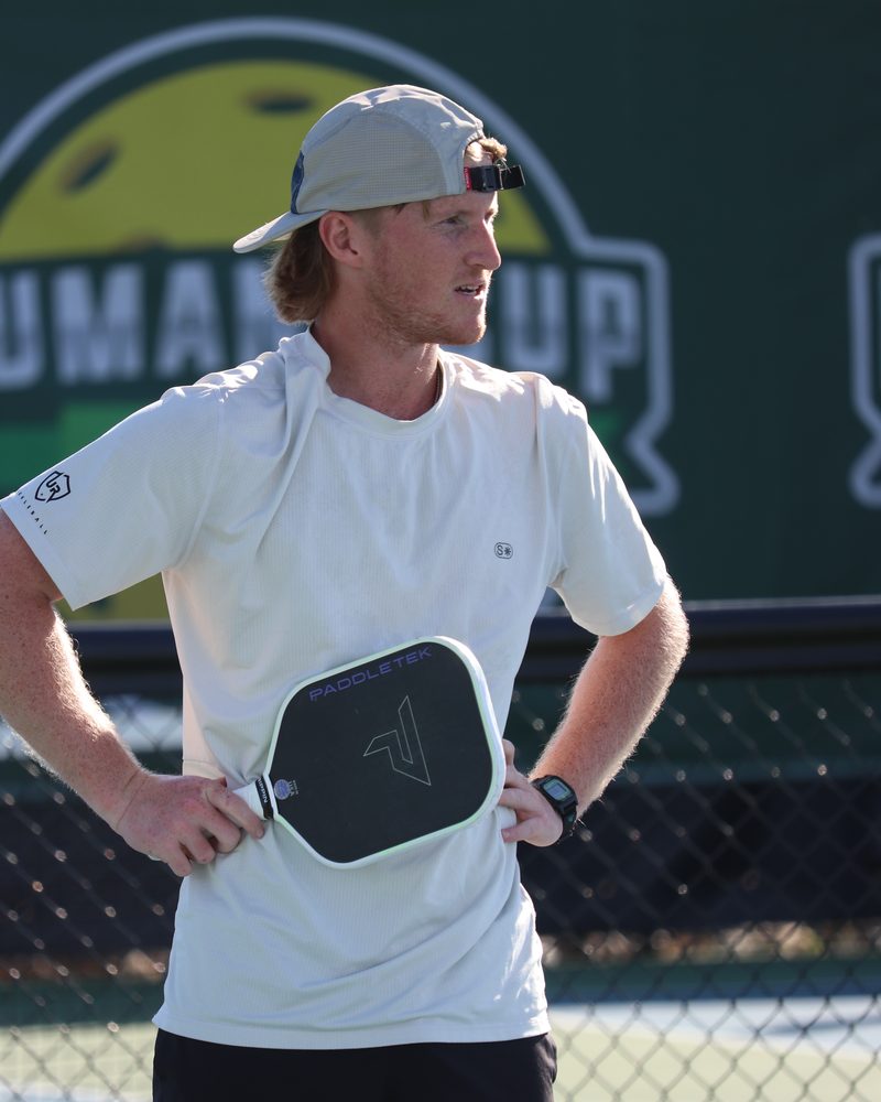 Clayton Boydston standing at the net with a paddle tucked under his arm.