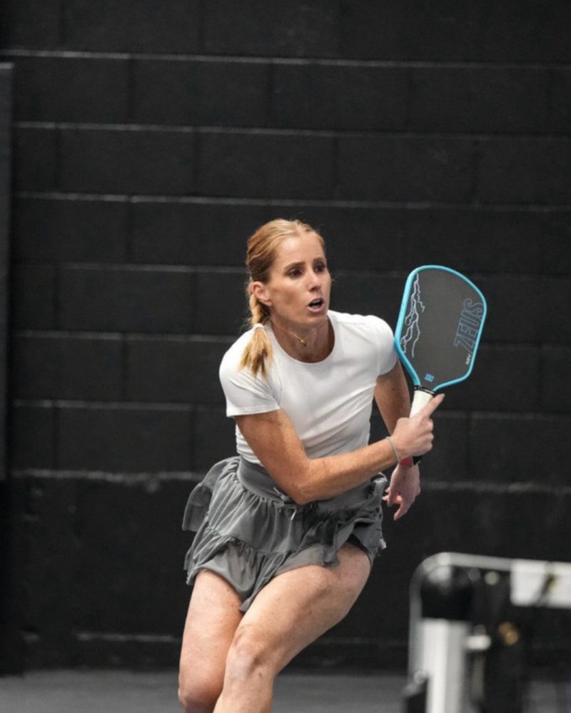 Liz Boydston moving to hit a pickleball shot on an indoor court.